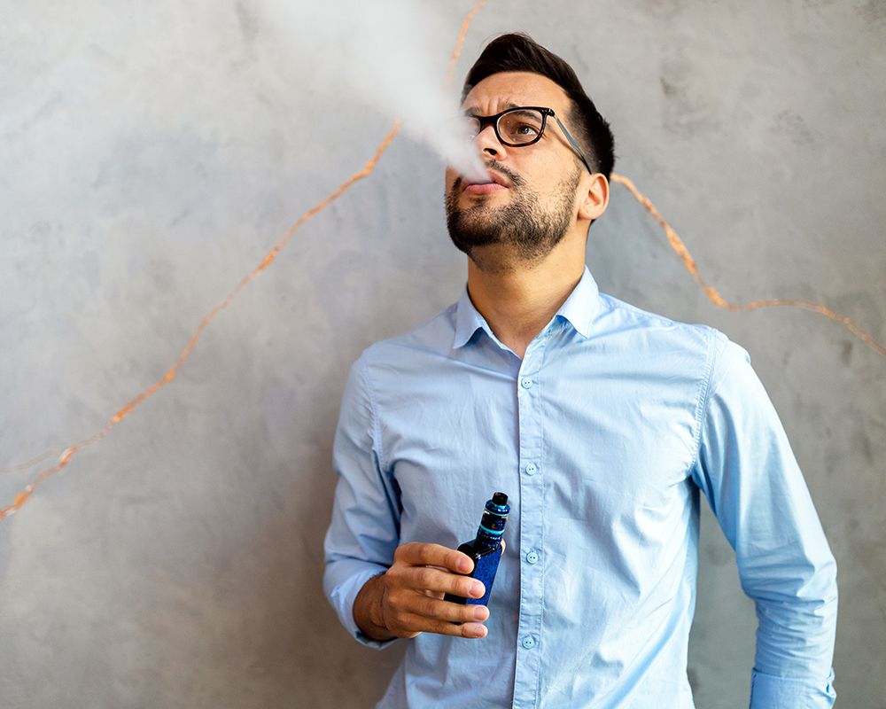 Chico vapeando con el cigarrillo electrónico en las manos.