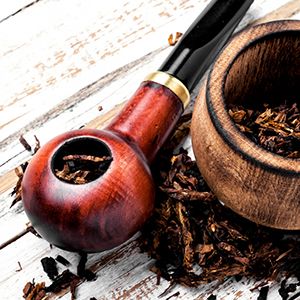 Pipa de madera con tabaco suelto en una mesa de madera.
