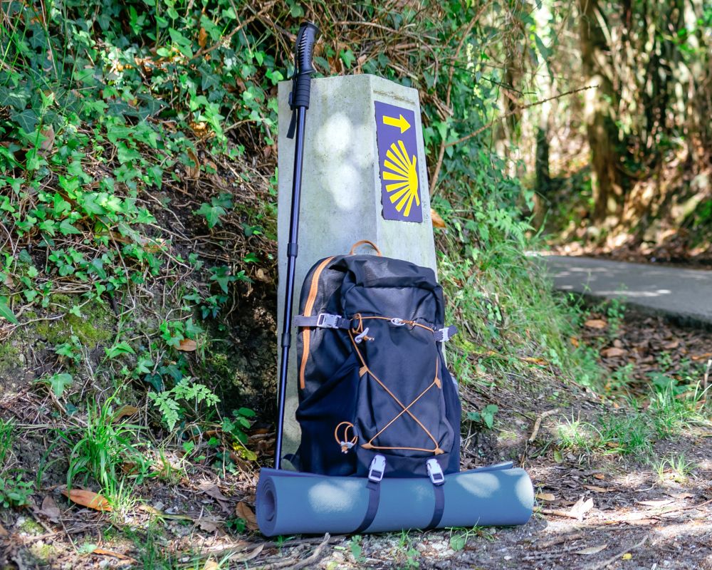 Mochila apoyada en una señal del camino de santiago. Concepto de Nanny bag.