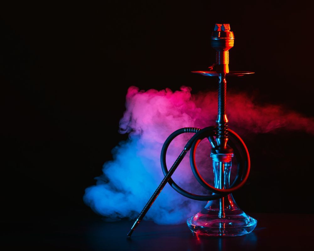 Imagen oscura con una shisha en primer plano.